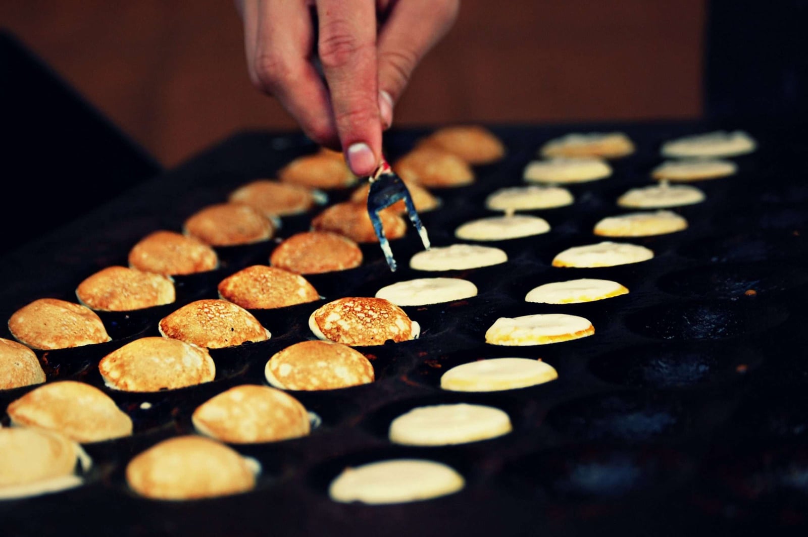 Poffertjes worden op een bakplaat gebakken bij De Poffertjesman