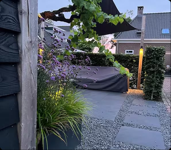 Tuinontwerp van Uit & Tuin met groene beplanting en een zithoek