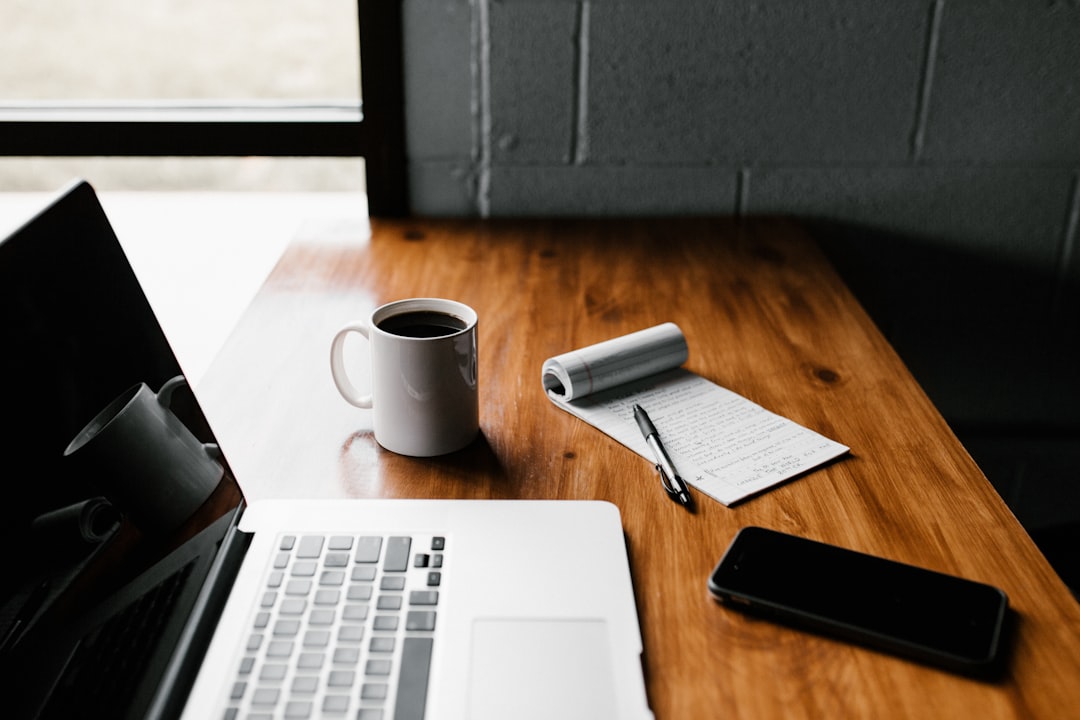 Terugkerende kosten website: laptop, koffiemok en smartphone op een bureau